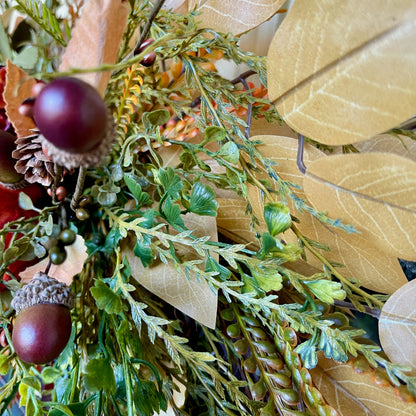 Close-up of a decorative wreath with leaves, berries, and acorns.