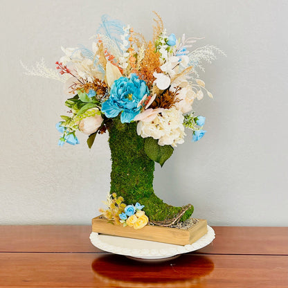 Moss-covered boot with a floral arrangement on a wooden surface