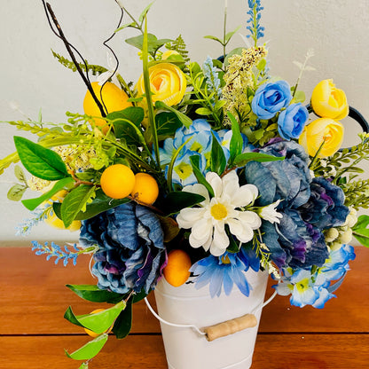 Bouquet of artificial flowers in a white bucket on a wooden surface