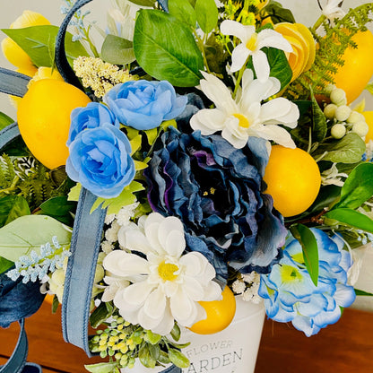 Bouquet with blue and white flowers, yellow lemons, and green leaves on a wooden surface.