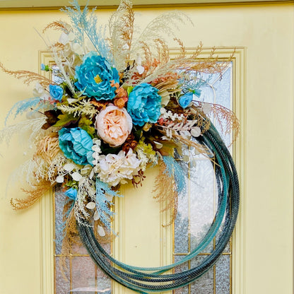 Decorative wreath with blue and pink flowers on a yellow door