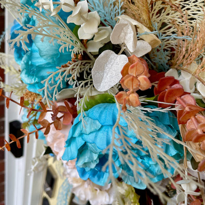 Decorative wreath with blue, orange, and white flowers on a door.