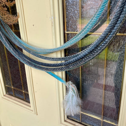 Coiled blue and gray rope with a tassel on a glass door