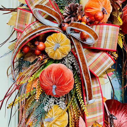 Decorative wreath with autumnal elements including pumpkins, ribbons, and foliage.