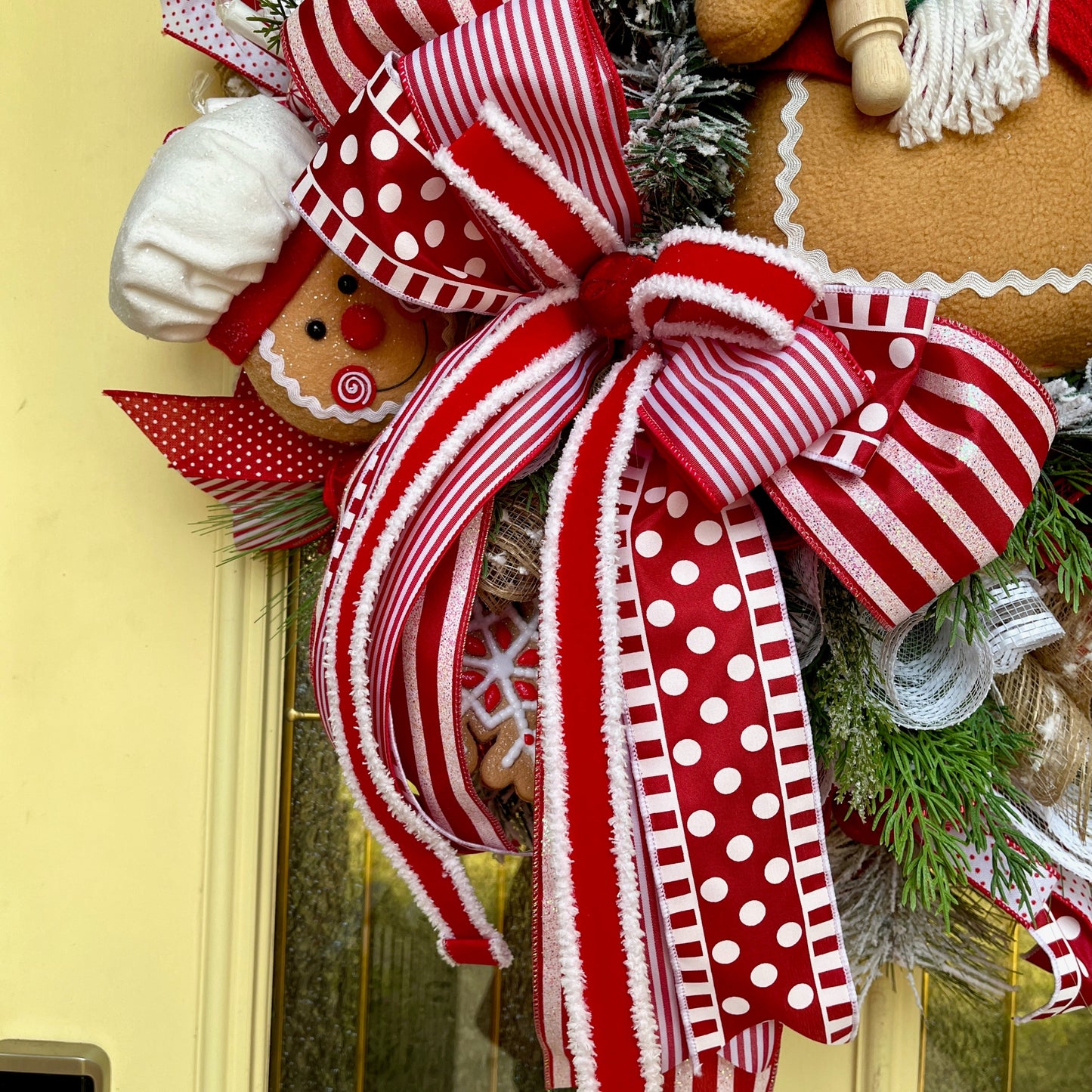 Decorative wreath with red and white polka dot bow on a yellow door