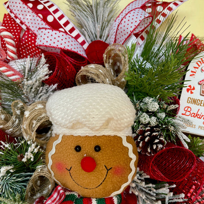 Decorative Christmas wreath with a gingerbread man design, surrounded by greenery and ribbons.