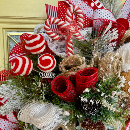 Decorative Christmas wreath with red and white candy cane ornaments, ribbons, and pine cones.