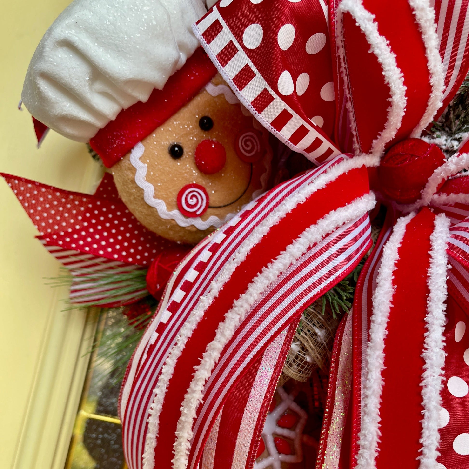 Decorative gingerbread man with a large red and white bow on a blurred background