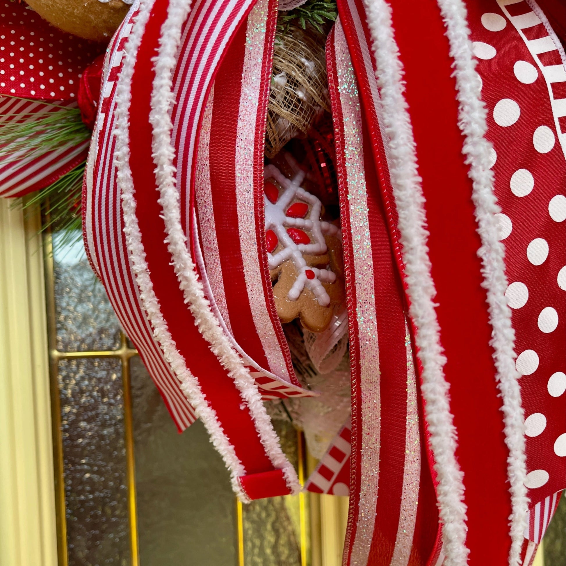 Close-up of a festive wreath with red and white ribbons and Christmas decorations.