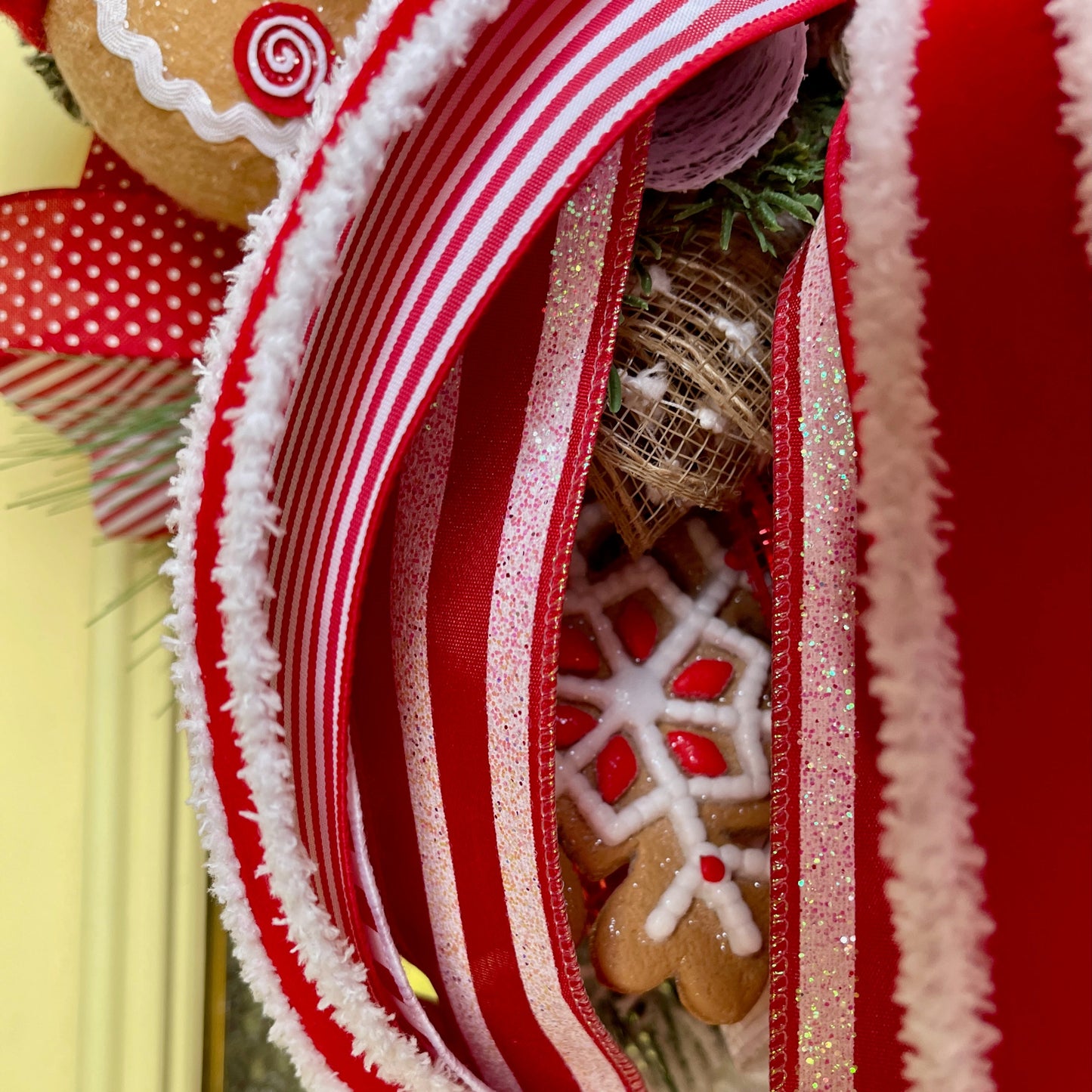 Close-up of a decorative wreath with red ribbons and gingerbread cookies.