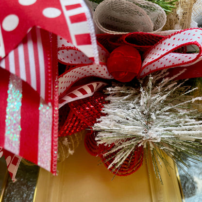 Decorative wreath with red and white ribbons and a gold bell.