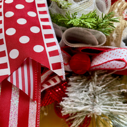 Close-up of red and white ribbons with a Christmas tree decoration in the background