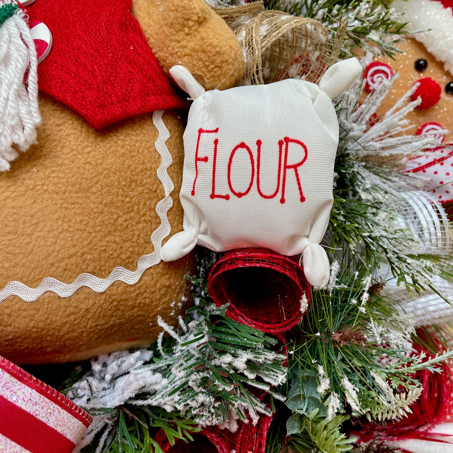 Decorative wreath with gingerbread man, reindeer, and 'FLOUR' container.