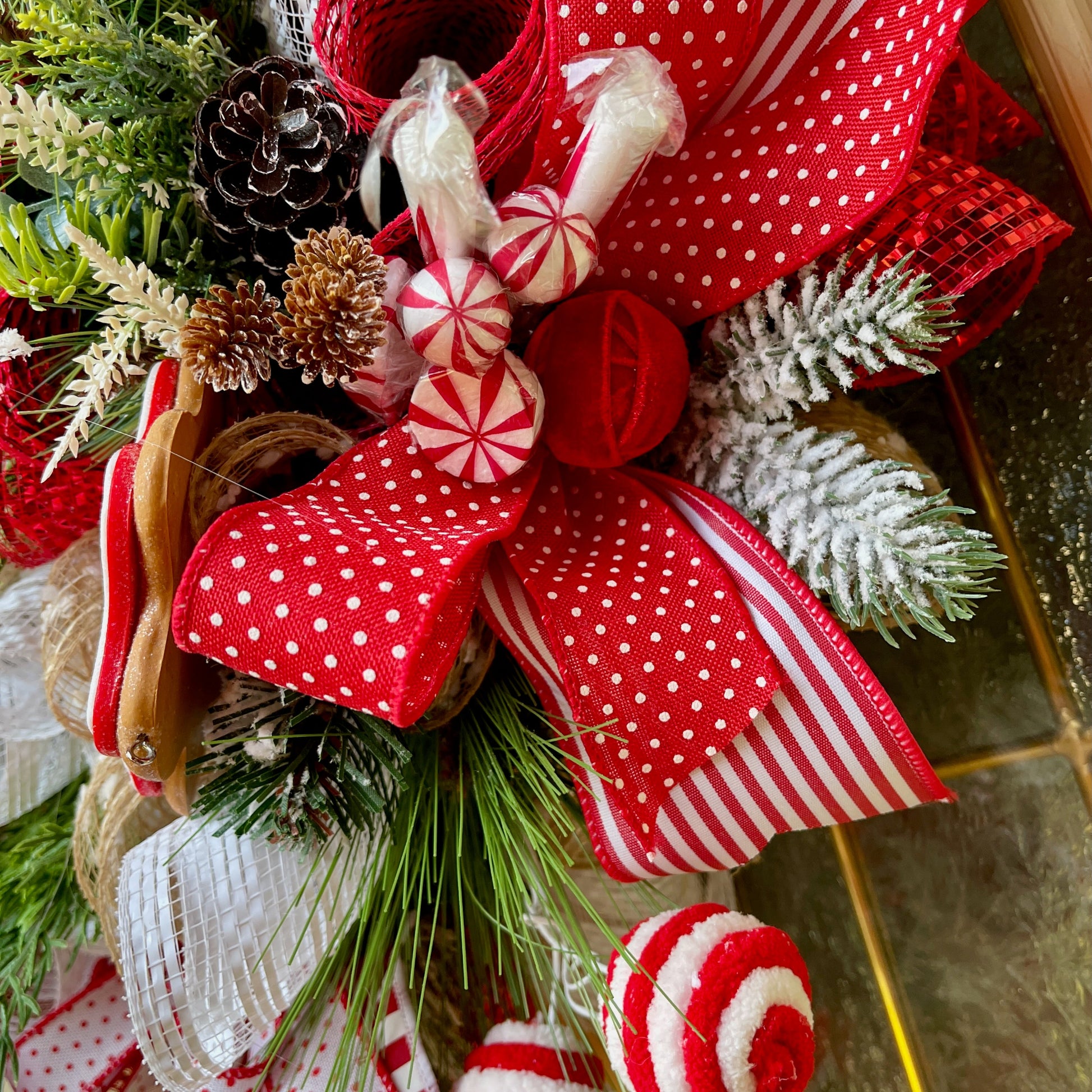 Decorative Christmas arrangement with red and white ribbons, pine cones, and candy canes.