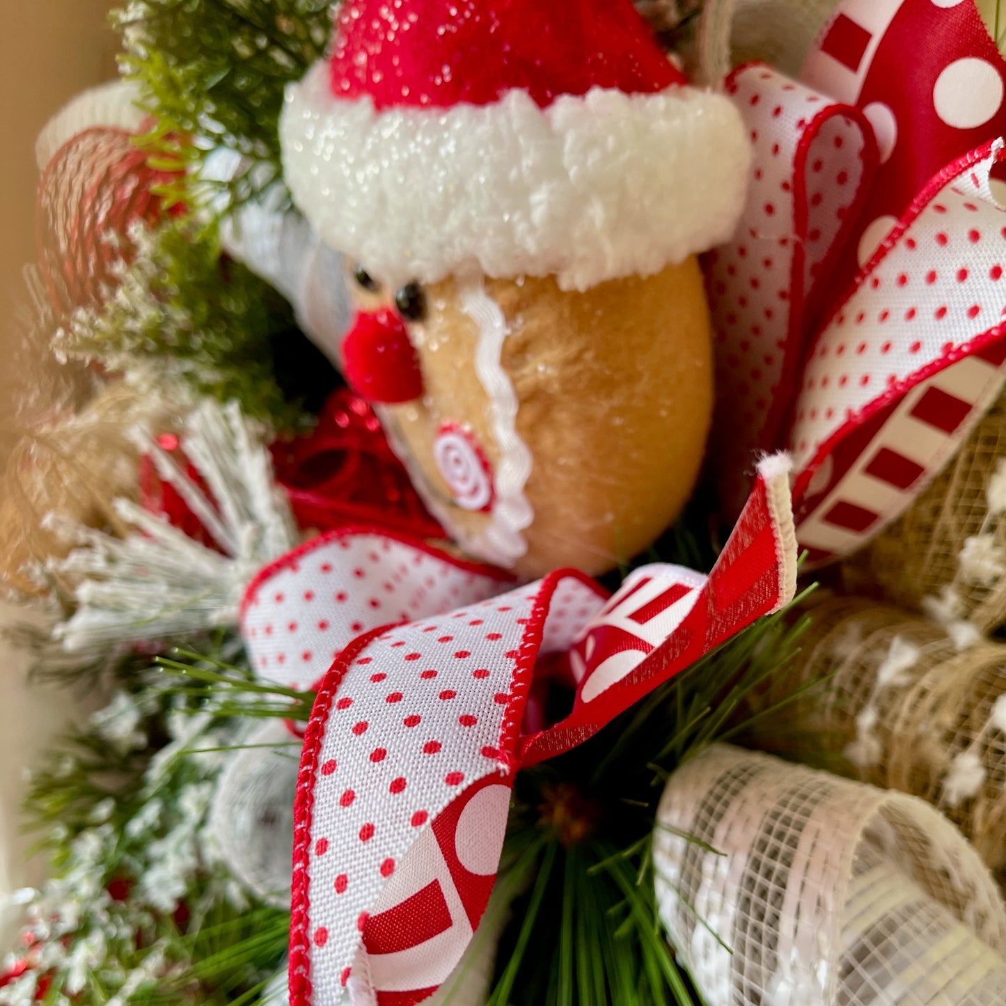 Decorative Christmas ornament with a reindeer face and red and white polka dot ribbon on a tree.