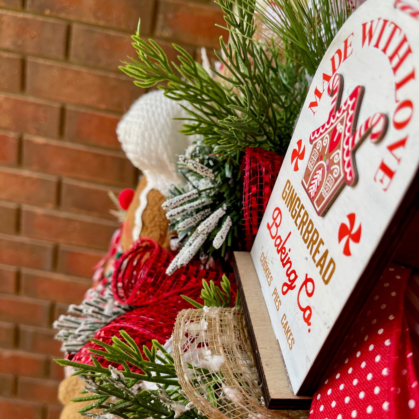Decorative Christmas scene with gingerbread house, greenery, and a sign reading 'Made with Love'.
