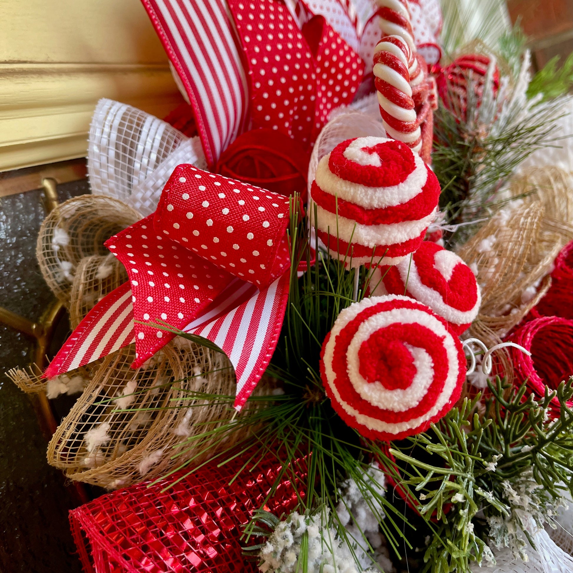 Decorative Christmas wreath with red and white ribbons, candy canes, and greenery.