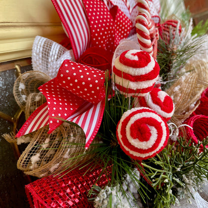 Decorative Christmas wreath with red and white ribbons, candy canes, and greenery.