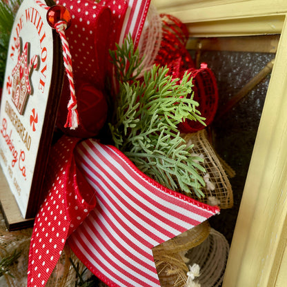 Decorative gift with red and white ribbon, greenery, and a gingerbread-themed tag.
