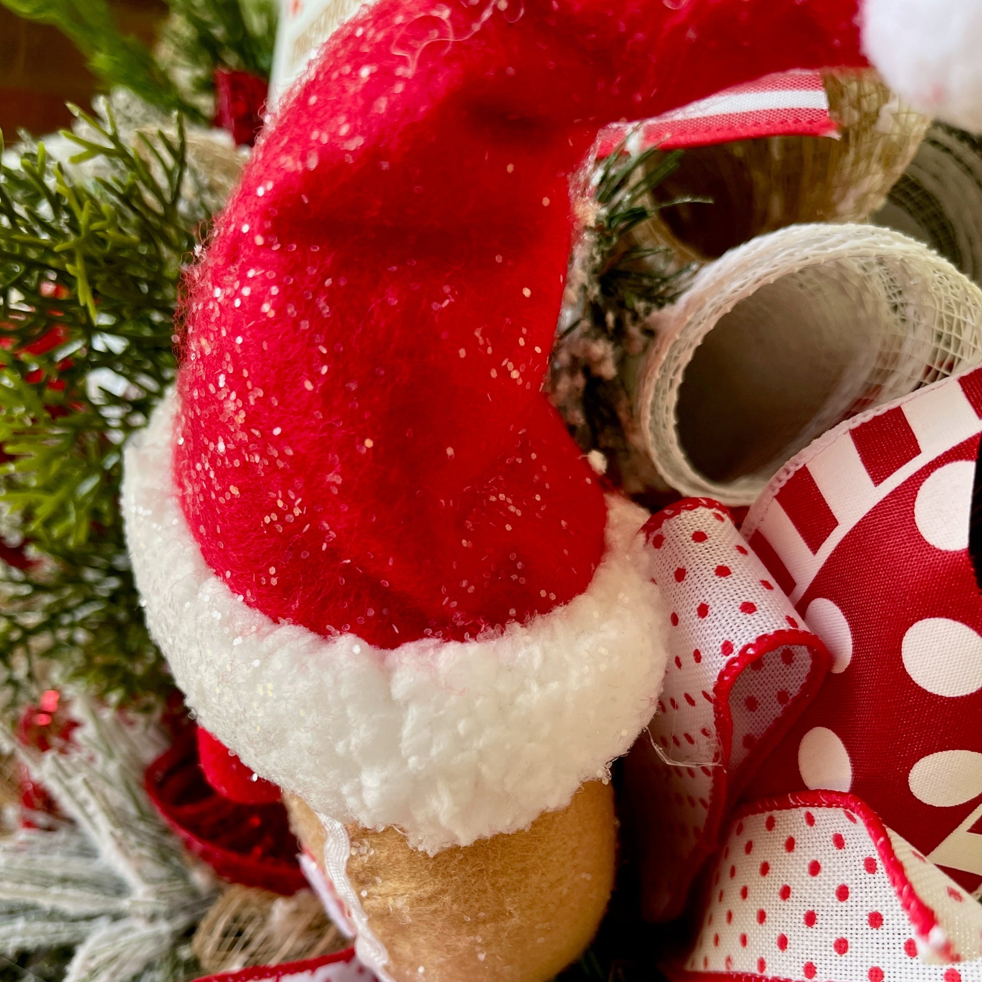 Decorative candy cane with red and white polka dot ribbon against a Christmas tree background