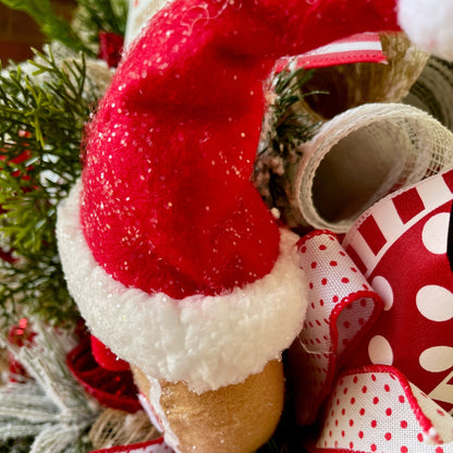 Decorative candy cane with red and white polka dot ribbon against a Christmas tree background