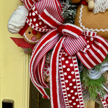 Decorative wreath with red and white ribbons and gingerbread man on a yellow door.