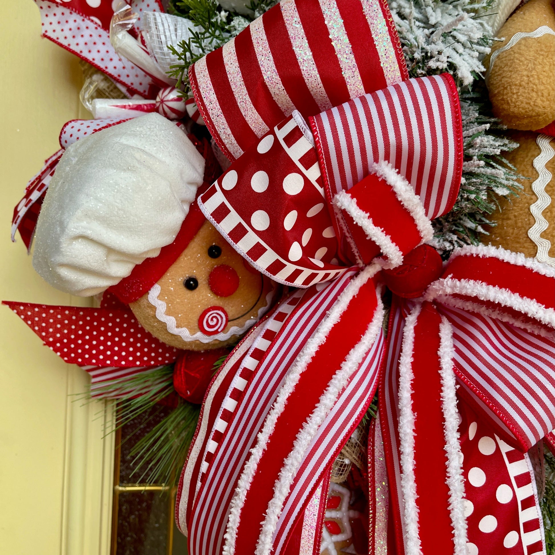 Decorative wreath with gingerbread man and large red bow on a door