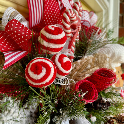Decorative Christmas wreath with red and white ribbons, candy canes, and pine cones.