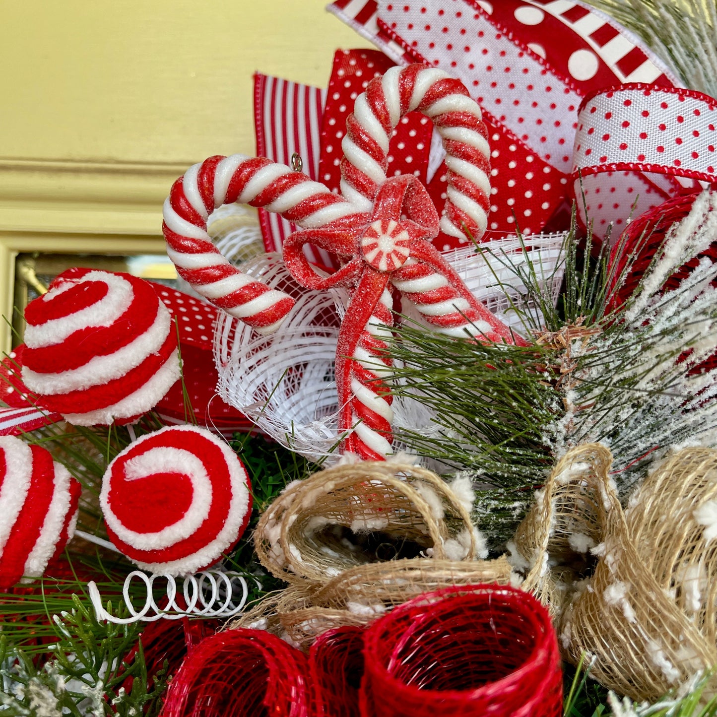 Decorative Christmas wreath with candy canes, ribbons, and pine branches.