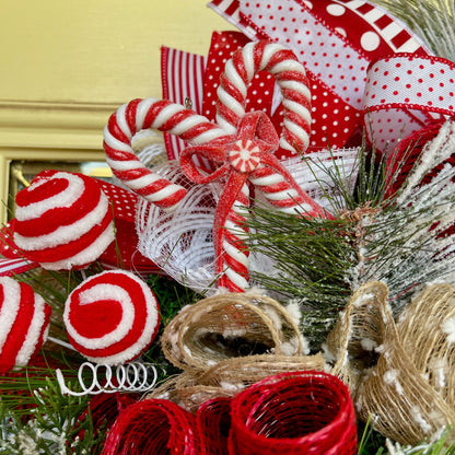 Decorative Christmas wreath with candy canes, ribbons, and pine branches.