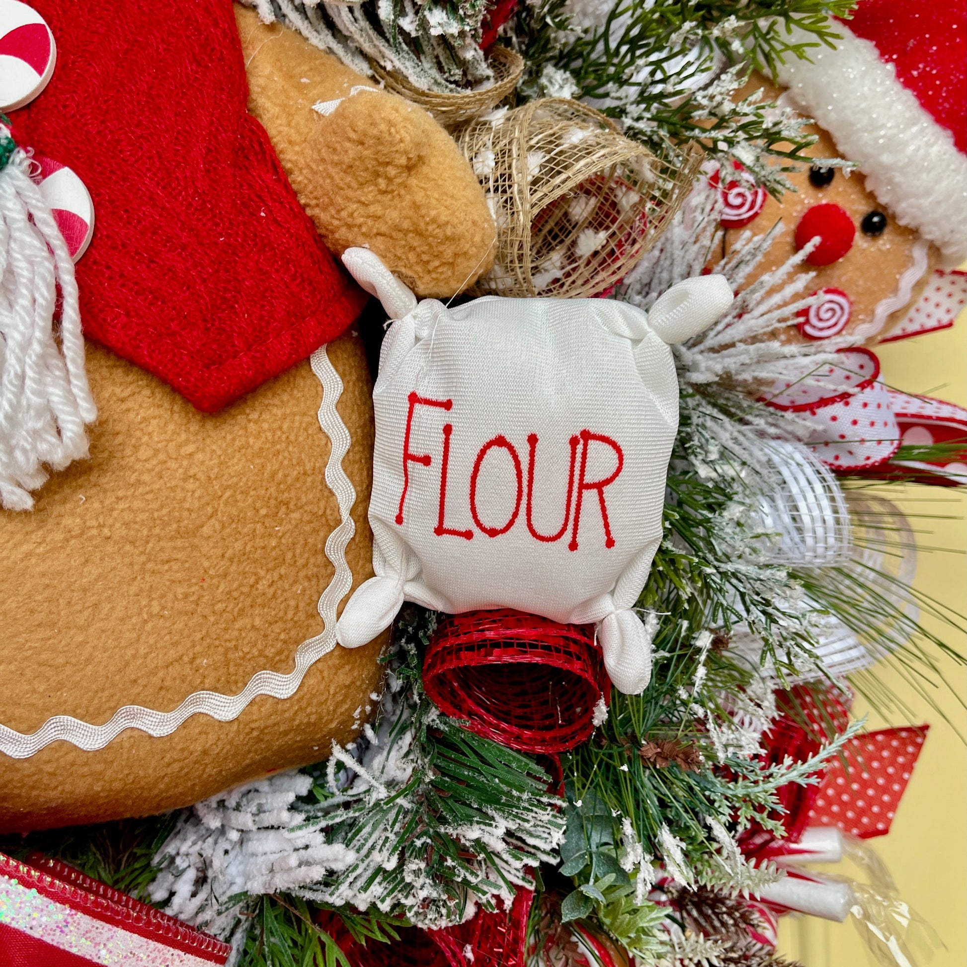 Decorative gingerbread man with 'FLOUR' label surrounded by Christmas elements on a yellow background